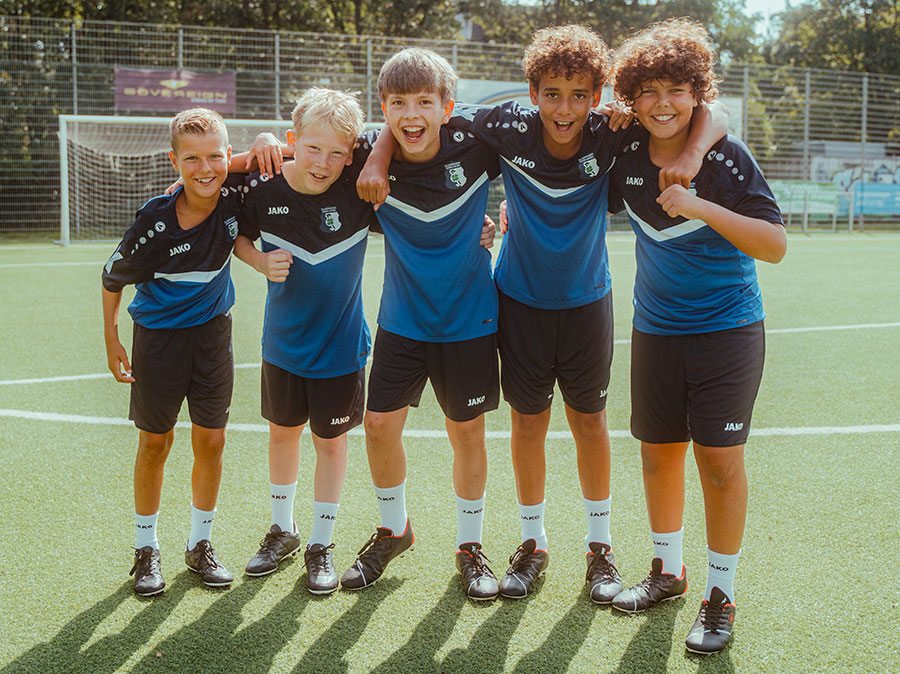 Un groupe d'enfants avec l'entraîneur des jeunes en survêtements JAKO