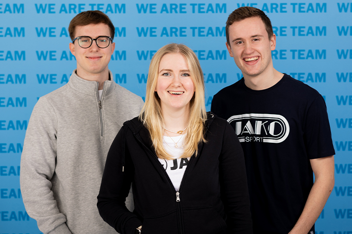 JAKO Auszubildende vor der WE ARE TEAM Wand