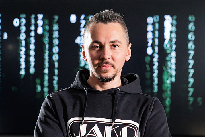 Mitarbeiter von JAKO vor einem Monitor, auf dem Quellcode geschrieben ist
