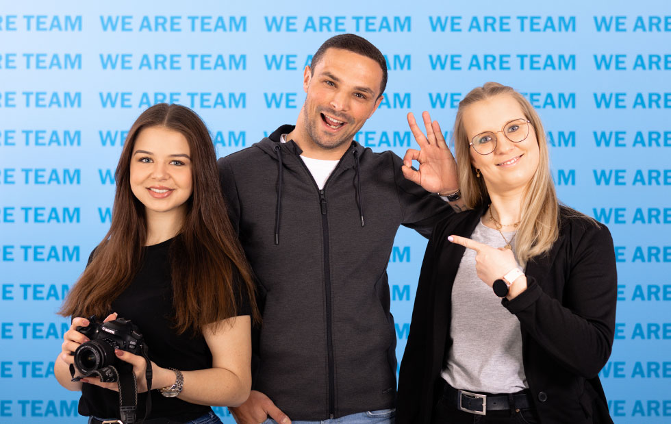 Mitarbeiter aus dem Marketing & Vertrieb bei JAKO vor der WE ARE TEAM Wand