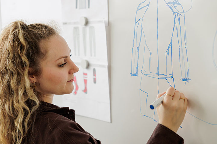 Mitarbeiterin von JAKO an einem Whiteboard mit Skizze von neuen Sportkleidungen